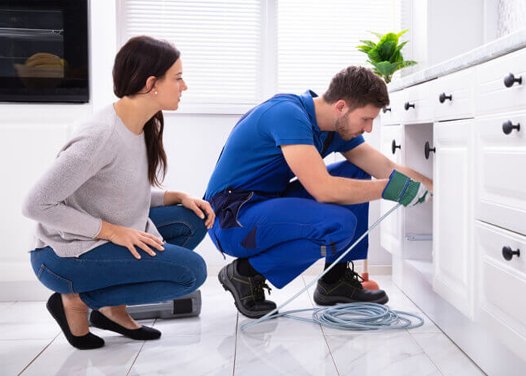 a women checking the plumbing boy while fixing the sink